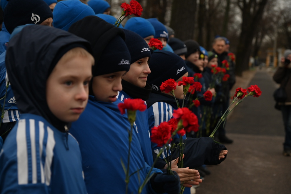 люди возлагают цветы к памятнику футболиста